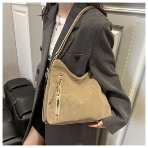 Close-up of beige soft leather tote with vertical gold zipper and long tassel detail