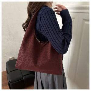 Deep red leopard print tote bag shown in a modern lifestyle setting on a model shoulder