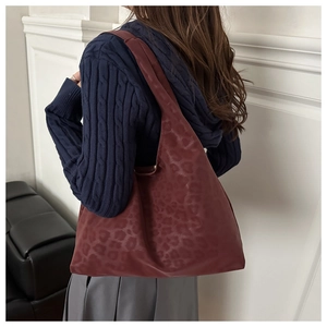 Close-up of matte dark red leopard print pattern on a large capacity leather tote bag