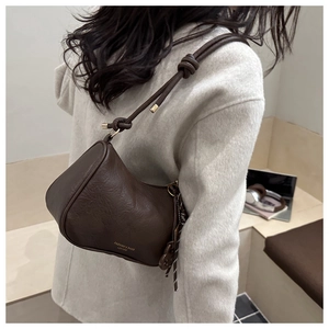 Detail of dark brown vintage textured leather shoulder bag on a light wool coat