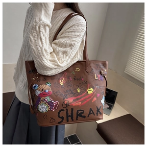 Detail of large brown tote bag showing leather texture and colorful bear graffiti art
