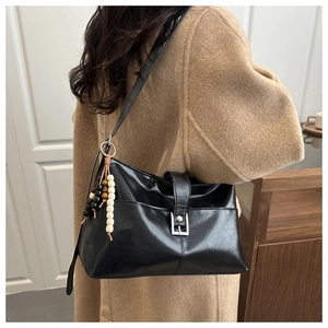 Vista laterale borsa tote in pelle nera con ciondolo di perline e fibbia metallica
