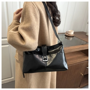 Dettaglio della borsa tote in pelle cerata nera con fibbia argentata indossata