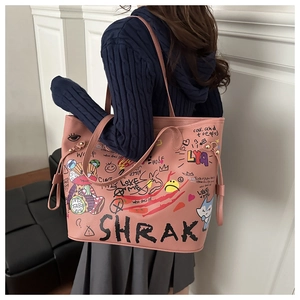 Détail du sac seau rose avec imprimés graffiti porté à l'épaule par un mannequin