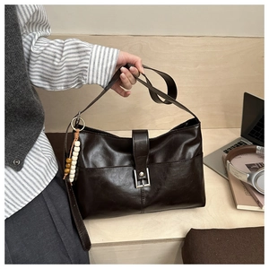 Dettaglio della borsa tote in pelle marrone con fibbia vintage e ciondolo di perle