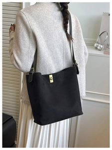 Model view of black suede shoulder bag with golden twist lock and adjustable strap