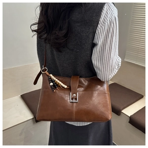 Dettaglio borsa a tracolla marrone vintage con fibbia metallica e nappa di perline decorativa