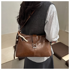 Dettaglio della borsa tote vintage marrone con texture lucida e ciondolo di perline