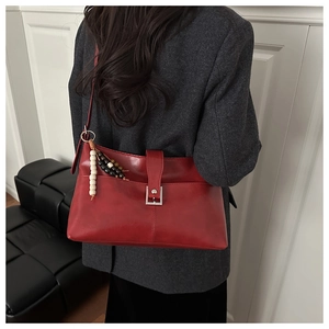 Dettaglio borsa tote in pelle rossa con ciondolo in legno e fibbia in argento