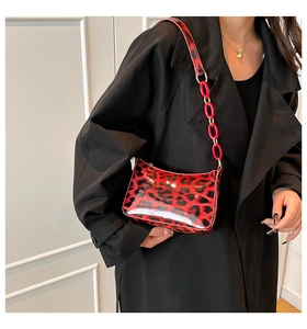 Detail of red leopard print crossbody bag with glossy finish and bold chain strap