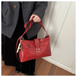 Dettaglio borsa shopper rossa in similpelle con fibbia e ciondolo in legno su blazer grigio