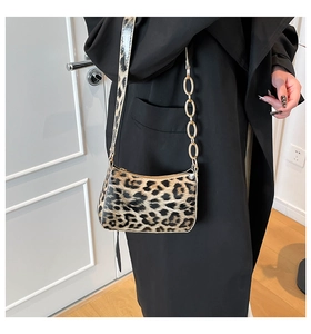 Detail of leopard print shoulder bag with gold chain and matching strap on black coat