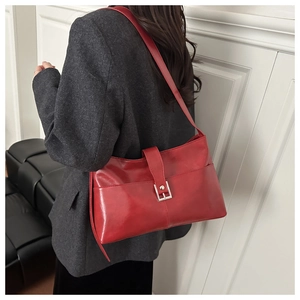 Vista laterale della modella con borsa tote rossa lucida e fibbia metallica decorativa