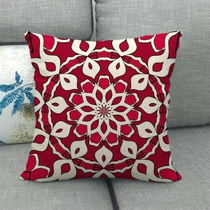 Close-up of bohemian red mandala pattern on linen pillowcase over a grey fabric sofa