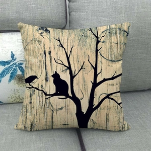 Close-up of linen pillowcase with cat and bird silhouette art on a gray sofa
