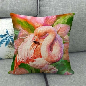 Linen pillowcase with flamingo and tropical leaves print on a grey fabric sofa