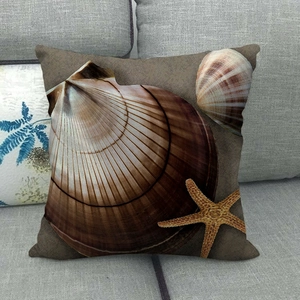 Linen pillow cover with ocean starfish and shell pattern on a grey fabric sofa