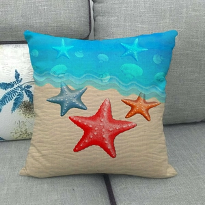 Close-up of square linen pillowcase with starfish and seashell patterns on a gray sofa