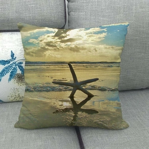 Close-up of a square linen cushion cover featuring a starfish on beach at sunset