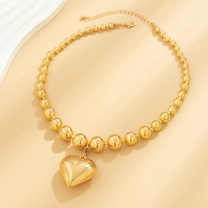 Close-up of golden beaded choker with a large puffy heart pendant and adjustable lobster clasp