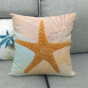 Close-up of linen cushion cover with starfish print on grey sofa, detailed fabric texture