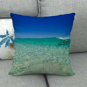 Detailed view of linen cushion cover featuring ocean wave print and GLIDE text on a sofa