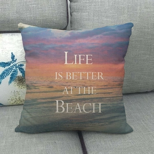 Close-up of linen pillow cover with beach sunset print on a grey sofa