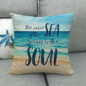 Close-up of linen pillowcase with beach print and inspirational sea soul quote on sofa
