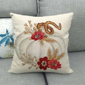 Gros plan d'une housse de coussin en lin avec citrouilles et fleurs de style rustique