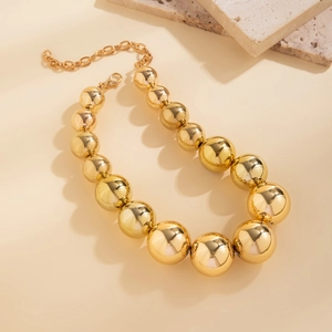 Gros plan sur un collier de perles dorées dégradées avec fermoir sur fond de pierre
