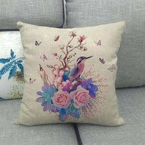 Linen cushion cover with watercolor bird and flower print on a grey sofa background
