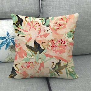 Detailed view of floral linen pillowcase with pink peony and crane patterns on a grey sofa