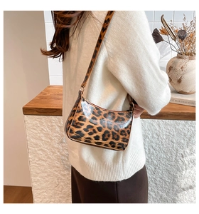 Chic leopard print underarm bag shown on model wearing white sweater in a cozy setting