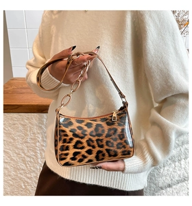 Detail shot of leopard print handbag with acrylic chain strap and golden zipper on white sweater