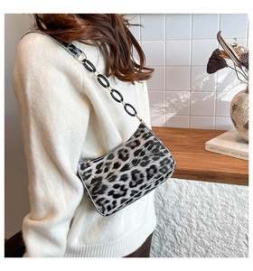 Detail of leopard print crescent bag with black acrylic chain strap on model shoulder