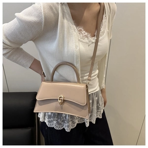 Close-up of beige leather handbag featuring a gold twist lock and elegant top handle