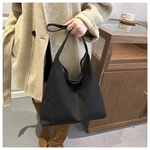 Close-up of the matte suede texture and wide strap on this black tote bag for women