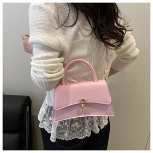 Détail d'un sac à bandoulière rose en similicuir avec fermoir doré sur le mannequin
