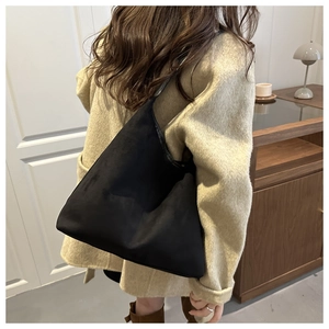 Detail view of large matte black shoulder tote bag paired with a stylish long beige coat