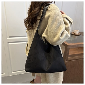 Close-up of black faux suede tote bag showing soft matte texture and leather strap details