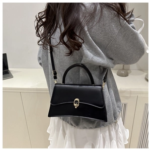 Detail view of the black leather crossbody bag with a gold buckle shown from the back