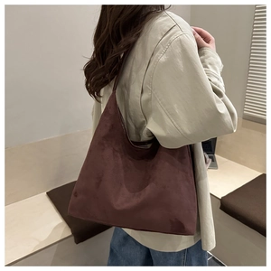 Detailed side view of deep brown suede tote bag carried by a model in casual style
