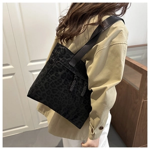 Detail of black leopard print nylon tote bag with drawstring and wide strap on shoulder