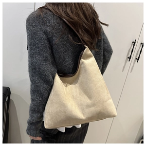 Close-up of cream suede hobo bag featuring dark brown contrast trim and a spacious design