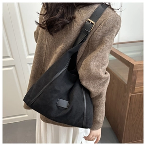 Detail of black large capacity canvas shoulder bag with adjustable strap on model