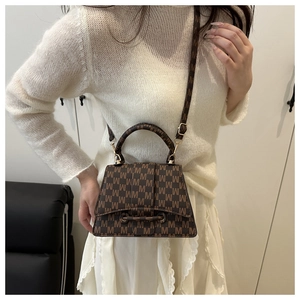 Detail of vintage crossbody bag with jacquard letter M pattern and leather handle