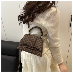 Detail view of brown textured square handbag with M-pattern print and gold hardware