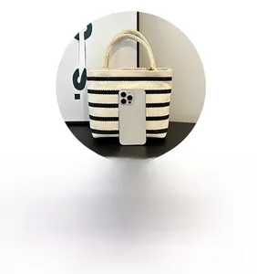 Close-up of small striped canvas tote bag compared to a phone for size reference