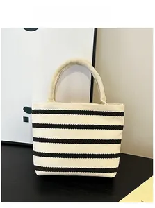 Detail of a minimalist canvas tote bag featuring classic black and white wide stripes