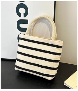 Detailed close-up of a small striped canvas tote bag with thick handles on a table